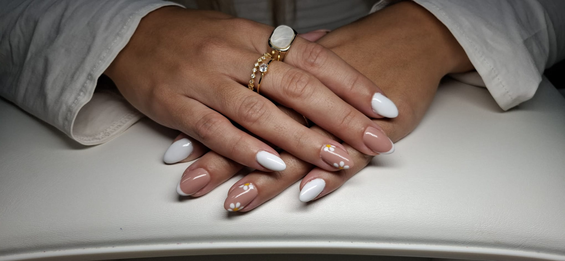 Manicure com margaridas brancas e pontas francesas sobre base nude